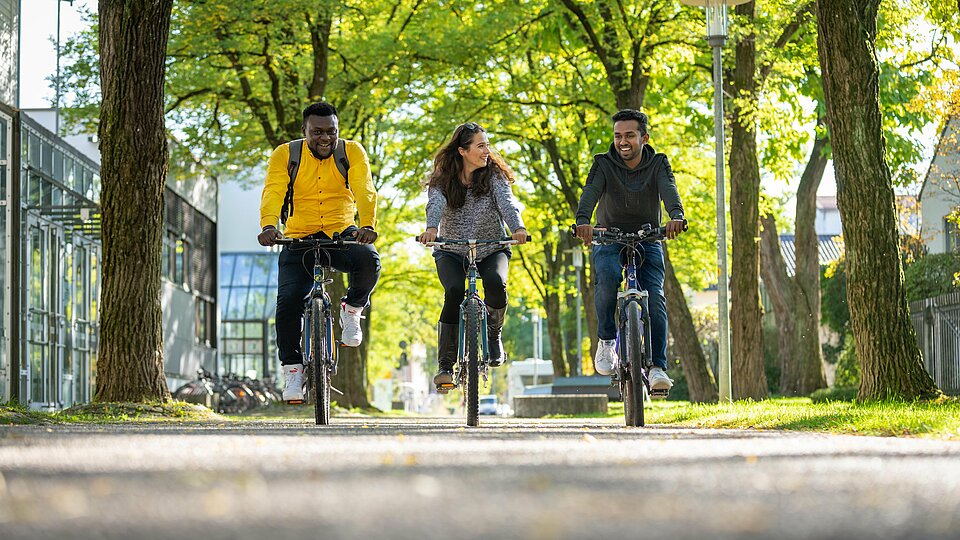 Students ride their bike on the Campus Rosenheim.