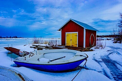 [Translate to English:] Verschneite Landschaft mit Haus und Boot