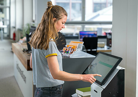 Nutzerin am Selbstverbuchungsgerät in der Bibliothek