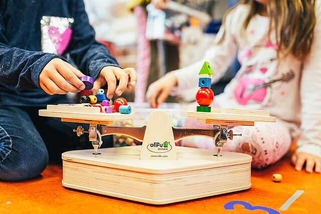 Zwei Kinder stapeln Holzteile auf ein Balancierbrett
