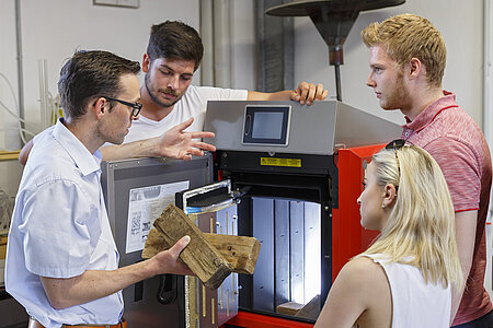 Professor F. Buttinger, EGT- Studiengangsleiter, erläutert EGT- Studierenden die Scheitholzbefüllung im EGT- Labor für Energie- und Umwelttechnik an der Technischen Hochschule Rosenheim 