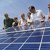 Das Bild zeigt Professor Frank Buttinger mit Studierenden auf einem Gebäude der Technischen Hochschule Rosenheim. Sie betrachten ein Solarmodul.