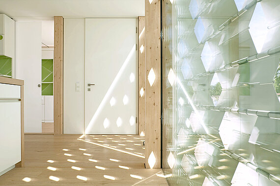 Blick in einen hellen Raum mit Holzboden und weißer Türe
