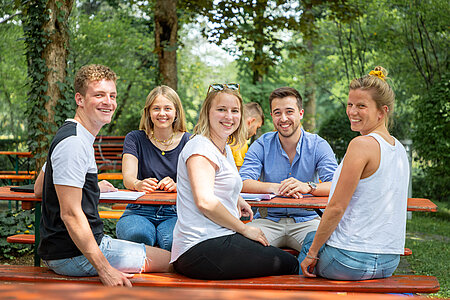 Gruppe Studierender am Biertisch sitzend vor der Mensa