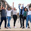 Auf dem Bild sind sechs Studierende der TH Rosenheim zu sehen. Sie befinden sich im Freien, auf der Treppen zwischen R- und S-Bau am Campus Rosenheim. Alle Studierenden heben freudig die Hände in die Höhe und jubeln.