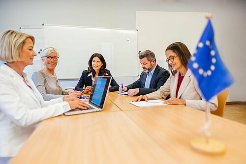 Personen sitzen an einem Tisch und arbeiten zusammen