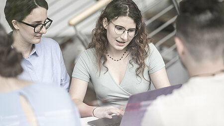 Two female students working on a laptop.