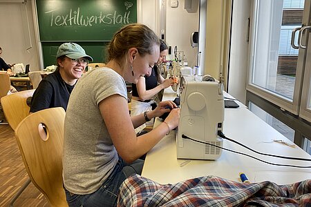 Das Bild zeigt eine Studentin, die an einer Nähmaschine arbeitet.