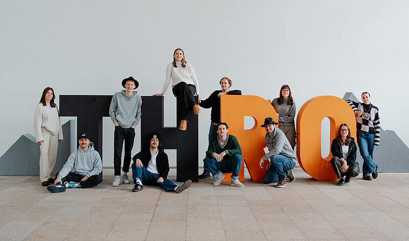 Gruppe Studierender steht zwischen den Buchstaben T, H, R und O