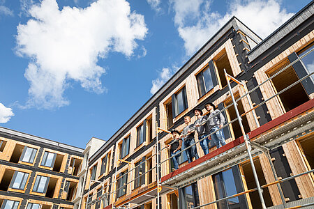 Studierende der Fakultät Holztechnik und Bau auf einem Baugerüst vor einem Holzgebäude