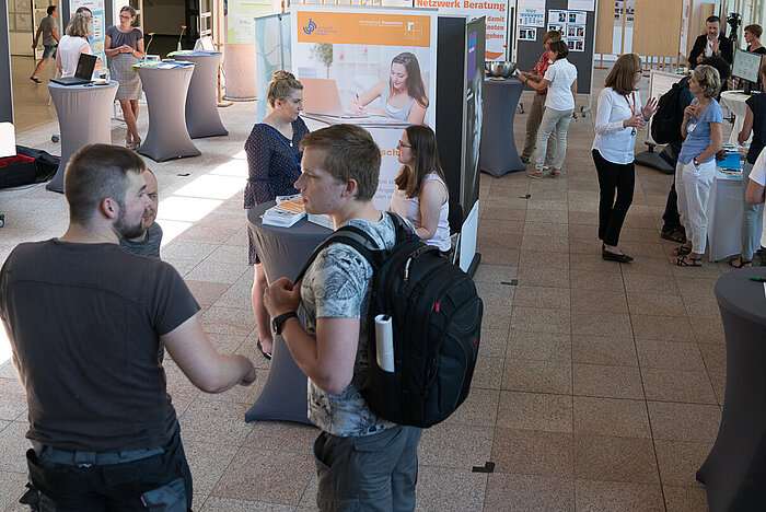 Das Bild zeigt Studierende und Lehrende an Stehtischen in der Technischen Hochschule Rosenheim.