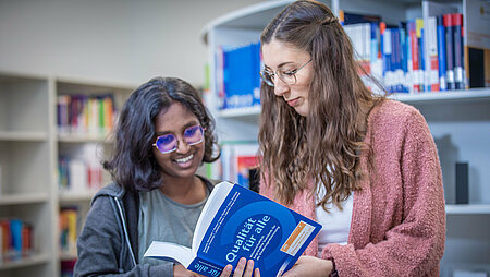Bibliothek Campus Muehldorf Zwei Studentinnen in der Campusbibliothek Mühldorf a. Inn schauen gemeinsam in ein Buch
