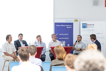 Fünf Männer (vier Vorredner sowie der Moderator) sitzen im Podium der Diskussionsrunde (links Dekan Reiner Hüttl)