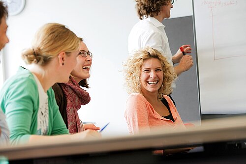 Drei Studentinnen lachend während einer Vorlesung