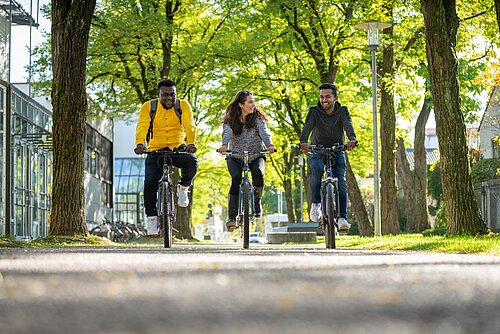 Studenten fahren mit dem Fahrrad am Campus Rosenheim.