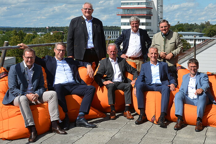 Das Bild zeigt eine Gruppe von Personen, darunter Wissenschaftsminister Markus Blume, auf einer Dachterrasse am Campus Burghausen der TH Rosenheim.