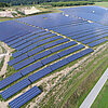 Das Bild zeigt einen Solarpark mit Hunderten von Solarpanelen an einem Hang.