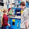 Das Bild zeigt Jugendliche an einer Maschine im Labor für Kunststofftechnik.