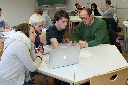 Studierende und Professor besprechen sich