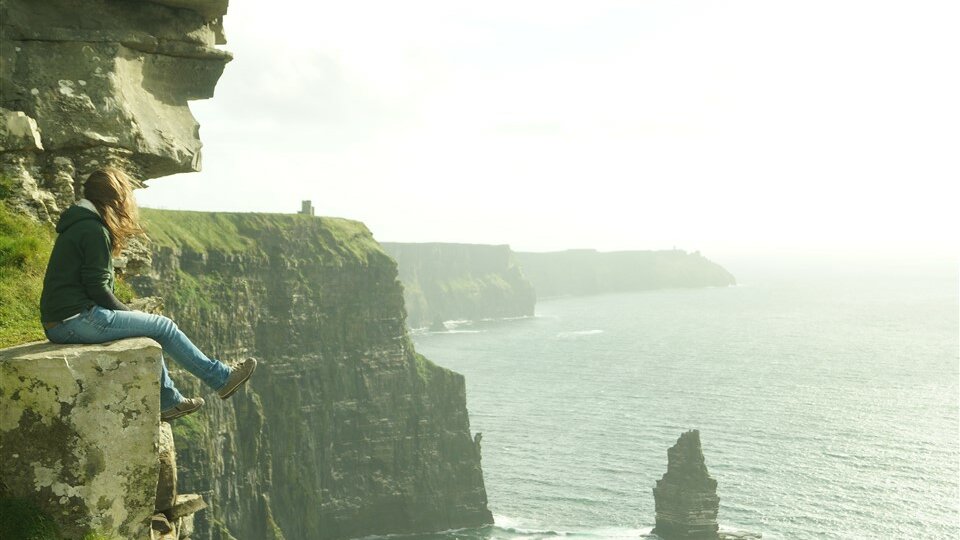 TH Rosenheim Outgoing-Studentin sitzt auf Steilklippe an der Küste Irlands.