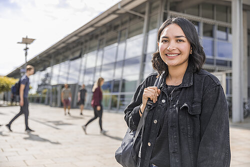 [Translate to English:] Bachelorstudentin der TH Rosenheim lächelnd auf dem Campus