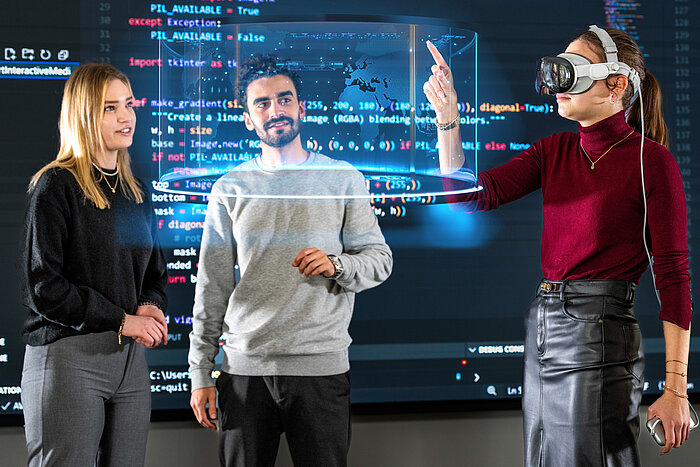 Das Bild zeigt drei Studierende, die mit einer VR-Brille arbeiten.