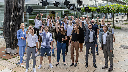 Studierende der Wirtschaftsinformatik feiern ihren erfolgreichen Abschluss beim Bachelor-Hüte-Werfen.