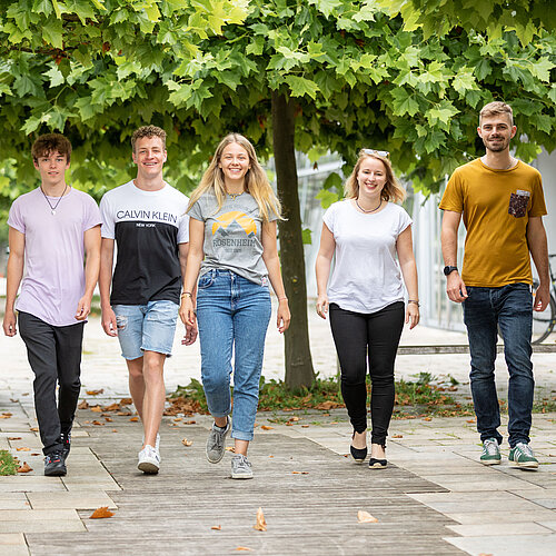 Studierende der TH Rosenheim nebeneinander laufend auf dem Campus