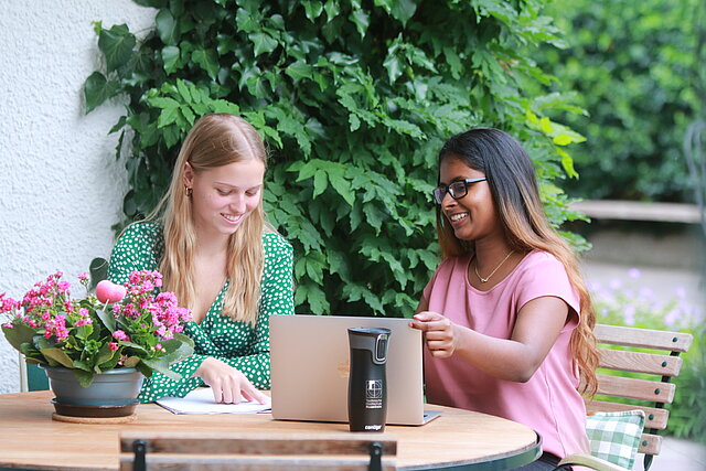 zwei Studierende der TH Rosenheim die am Laptop im Garten arbeiten