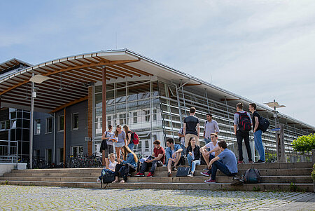 [Translate to English:] Mehrere studierende der TH Rosenheim sitzen und stehen auf einer Treppe im Campus Rosenheim.