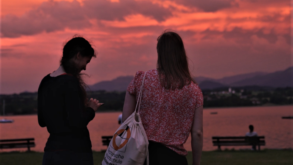 Two students looking at a sunset at lake Simssee.