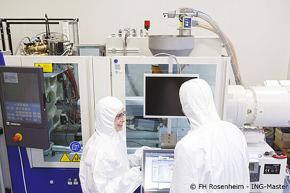 Studierende in Reinraumbekleidung vor einer Spritzgussmaschine