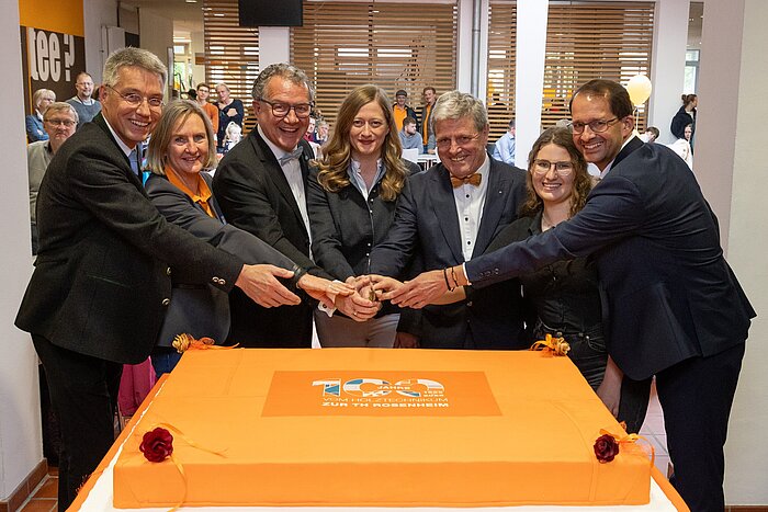 Das Bild zeigt eine Gruppe von Personen vor der Geburtstagstorte beim Tag der offenen Tür.