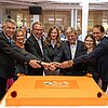 Das Bild zeigt eine Gruppe von Personen vor der Geburtstagstorte beim Tag der offenen Tür.