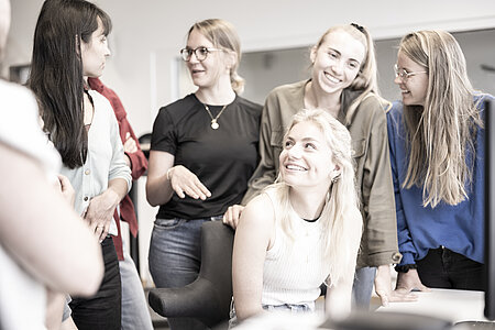 Studentinnen unterhalten sich lachend im Klassenraum