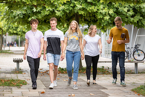 [Translate to English:] Eine Gruppe Studierender der TH Rosenheim nebeneinander laufend am Campus 