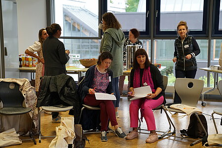 Zwei Frauen sitzen im Stuhlkreis im Workshopraum und arbeiten.