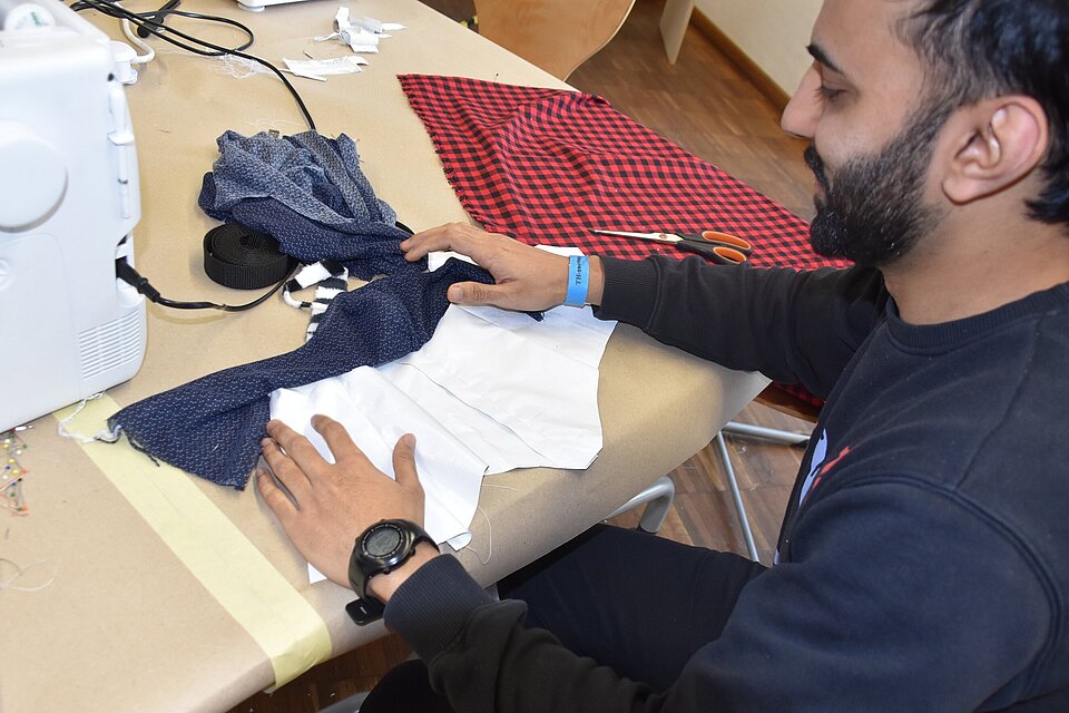 Das Bild zeigt den Studenten Zaryab Kahn an einer Nähmaschine.