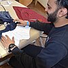 Das Bild zeigt den Studenten Zaryab Kahn an einer Nähmaschine.
