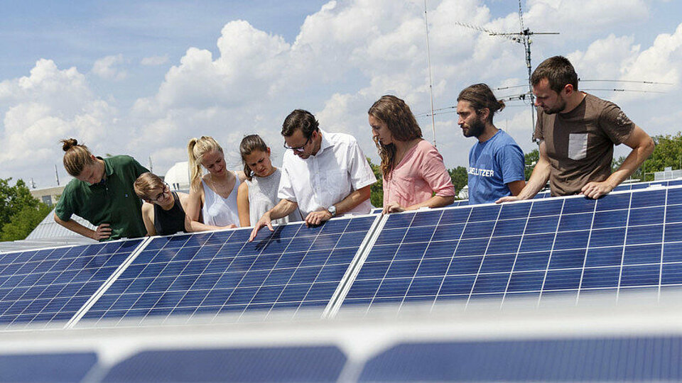 Students and their professor explore solar panels on a rooftop.