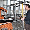 Das Bild zeigt zwei Schüler, die einen Roboter testen.