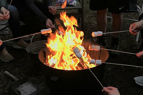 Studenten grillen Marshmallows an einem Lagerfeuer.