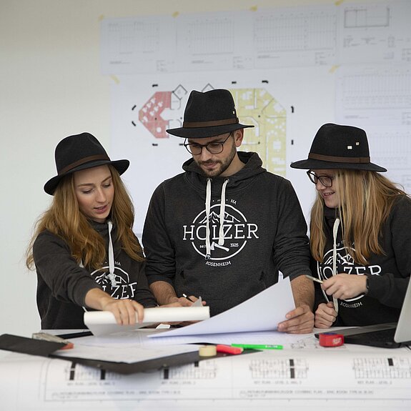Drei Studierende Innenausbau mit Holzer Hut