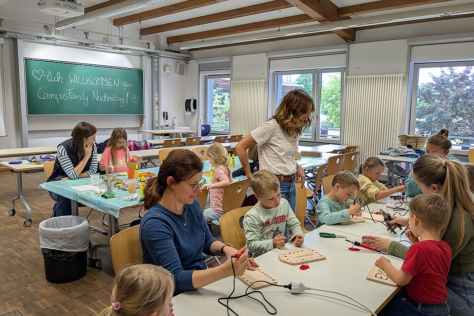 Kinder und Eltern beim gestalten von Schneidebrettern
