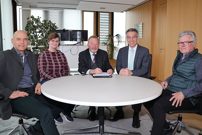 Das Bild zeigt fünf Personen, die an einem Tisch sitzen.