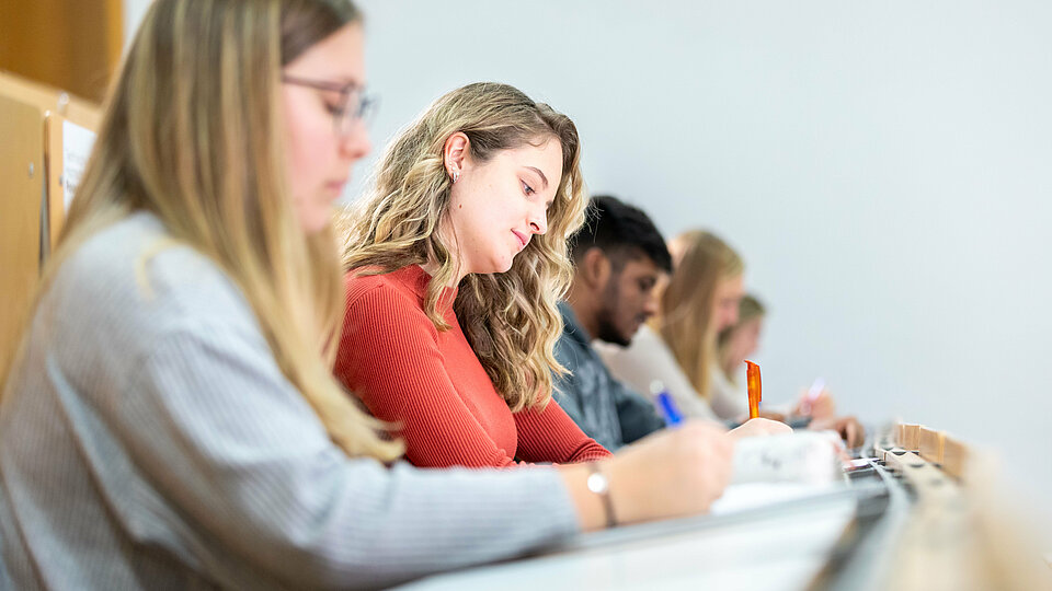 Studentinnen und Studenten im Hörsaal in einer Reihe