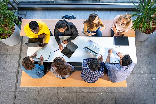 Studierende sitzen an einem Tisch zusammen