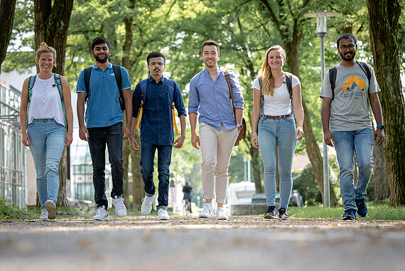 Group of international students walking side by side under trees