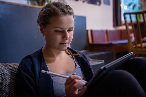 Studentin zu Hause mit Tablet auf den Knien