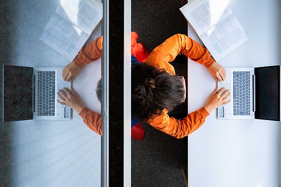 Studentin am Latop von oben mit Spiegelung im Hintergrund